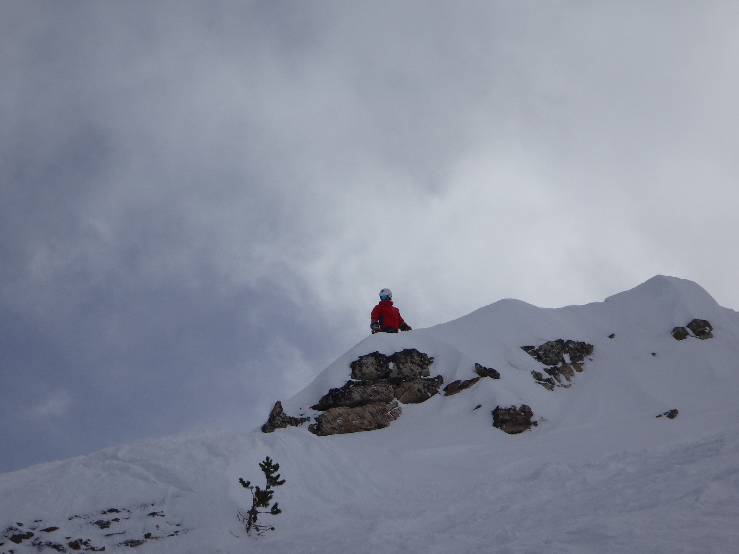 A skier on a wind-scoured ridge under a winter sky